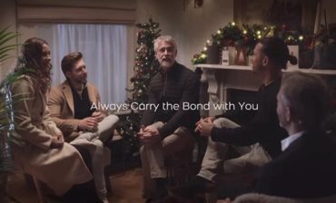 A group of people sitting and talking in a cozy, decorated room with Christmas lights.