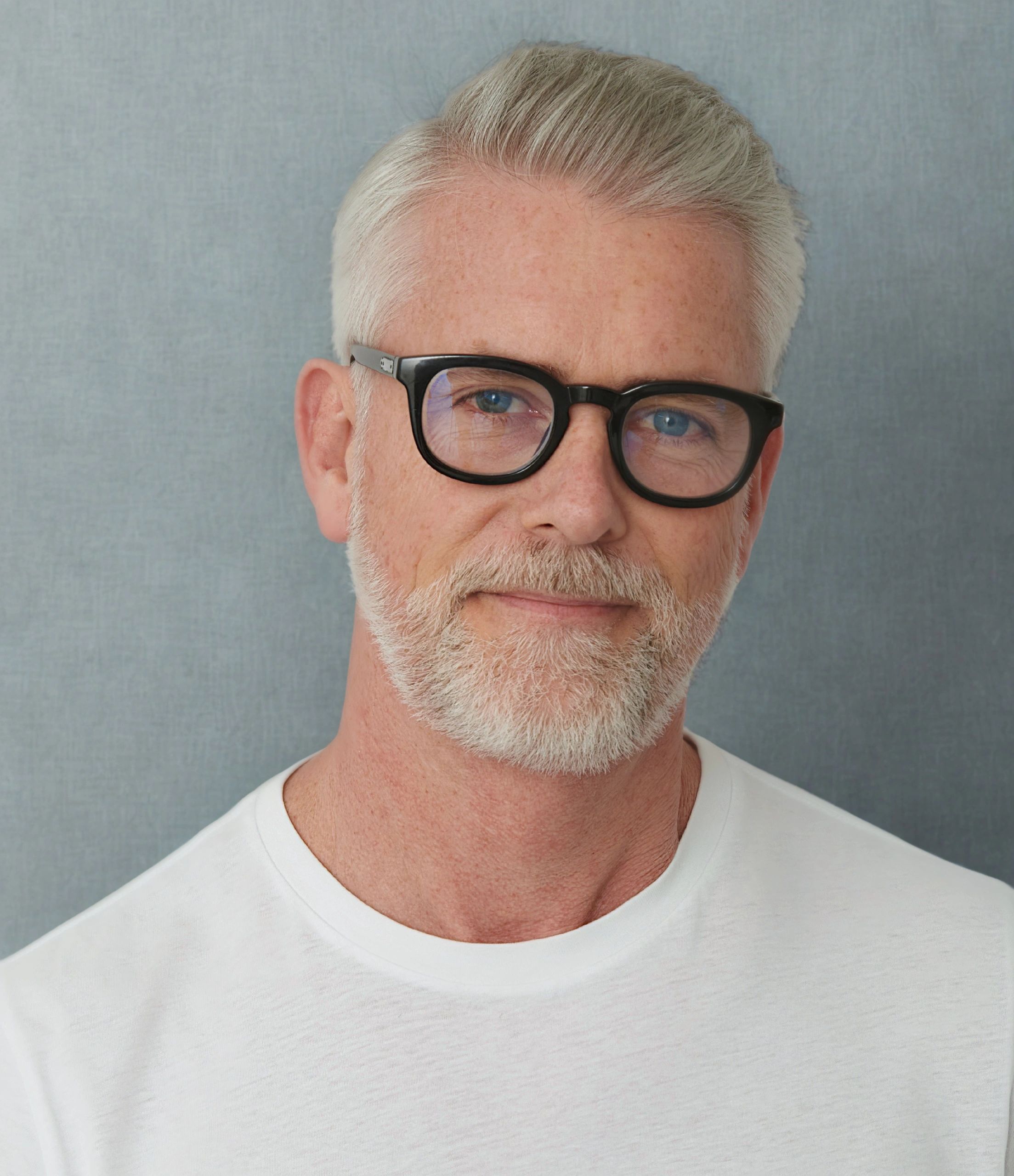Smiling older man with white hair and glasses.