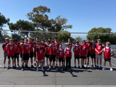 Youth basketball team posing on outdoor court in red jerseys under clear sky.