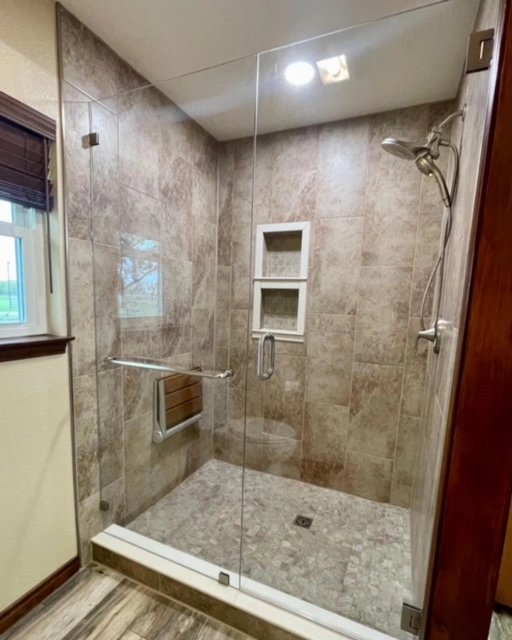Modern glass shower with tiled walls and built-in shelves.