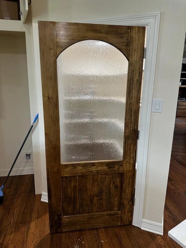 A wooden door with frosted glass panel in a home interior.