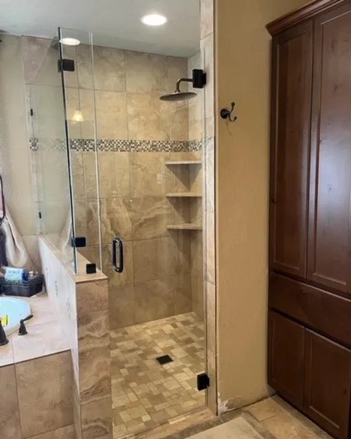 Modern bathroom with glass shower enclosure and tiled walls.