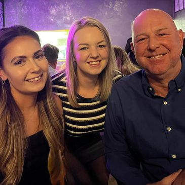 Three people smiling together in a cozy indoor setting.