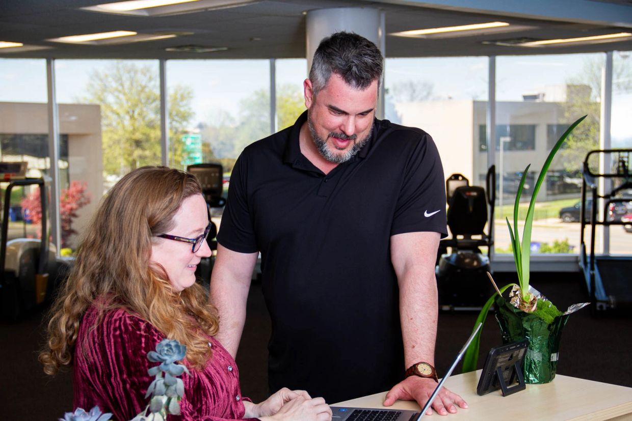 Two colleagues collaborating over a laptop in a bright office space.