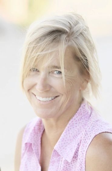 Smiling woman with blonde hair in a pink sleeveless top.
