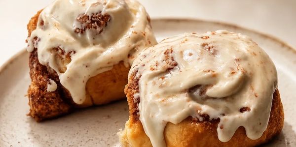 Two cinnamon rolls with creamy icing on a plate.