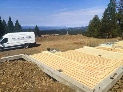 Frontier Plumbing van at a new construction site overlooking a mountain view. 