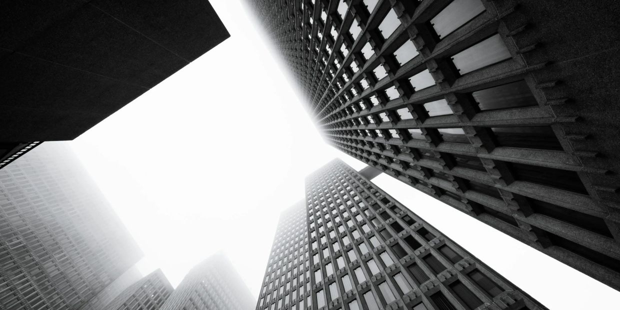 Looking up at tall skyscrapers in black and white.