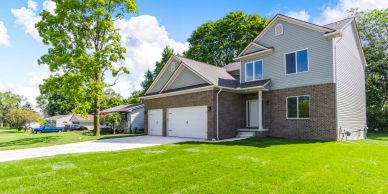Modern two-story suburban house with a large garage and green lawn.