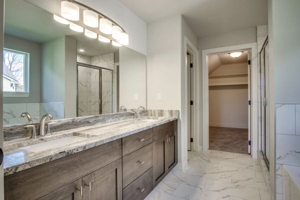 Modern bathroom with double sinks, marble countertop, and walk-in closet.