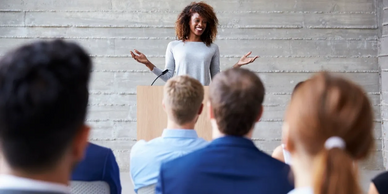 Person standing at a podium talking to an audience.