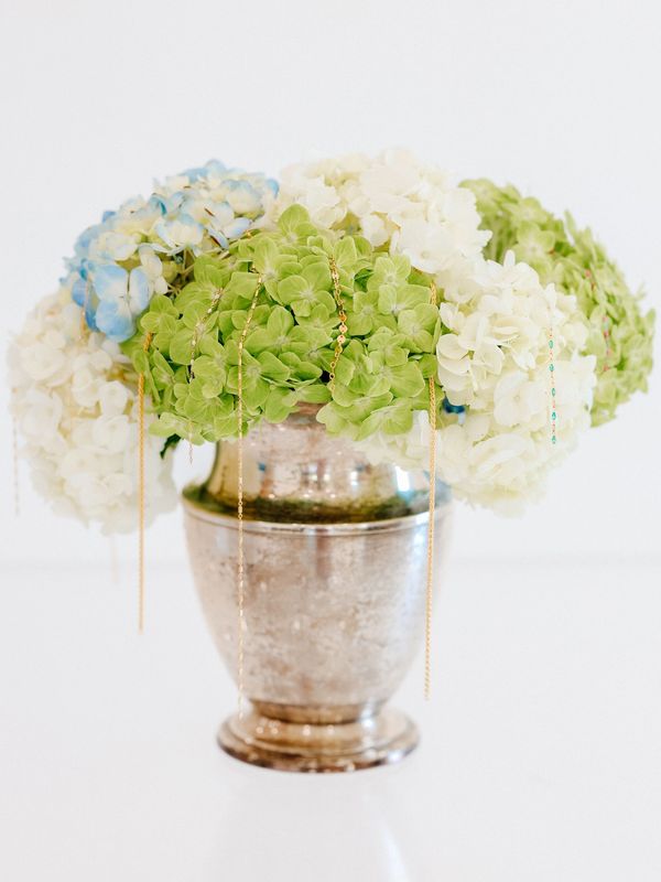 Elegant hydrangea bouquet with delicate gold chains in a vintage silver vase.
