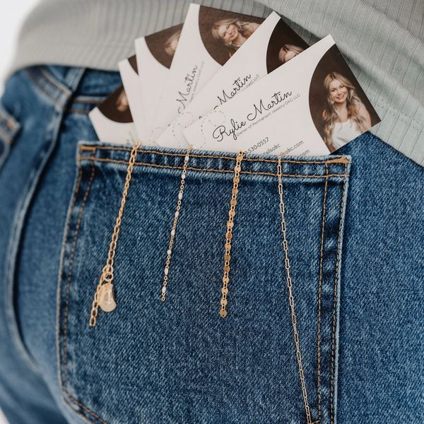 Business cards and gold chains tucked into a denim back pocket.