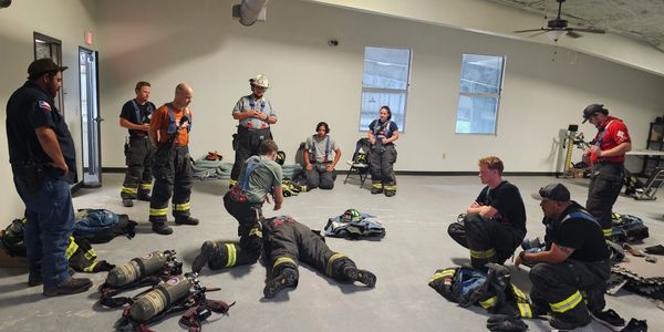 Firefighters training indoors with equipment.