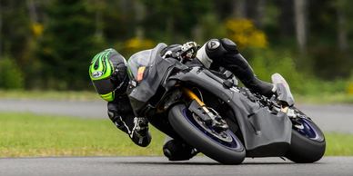 Motorcyclist leaning into a sharp turn on a racetrack.