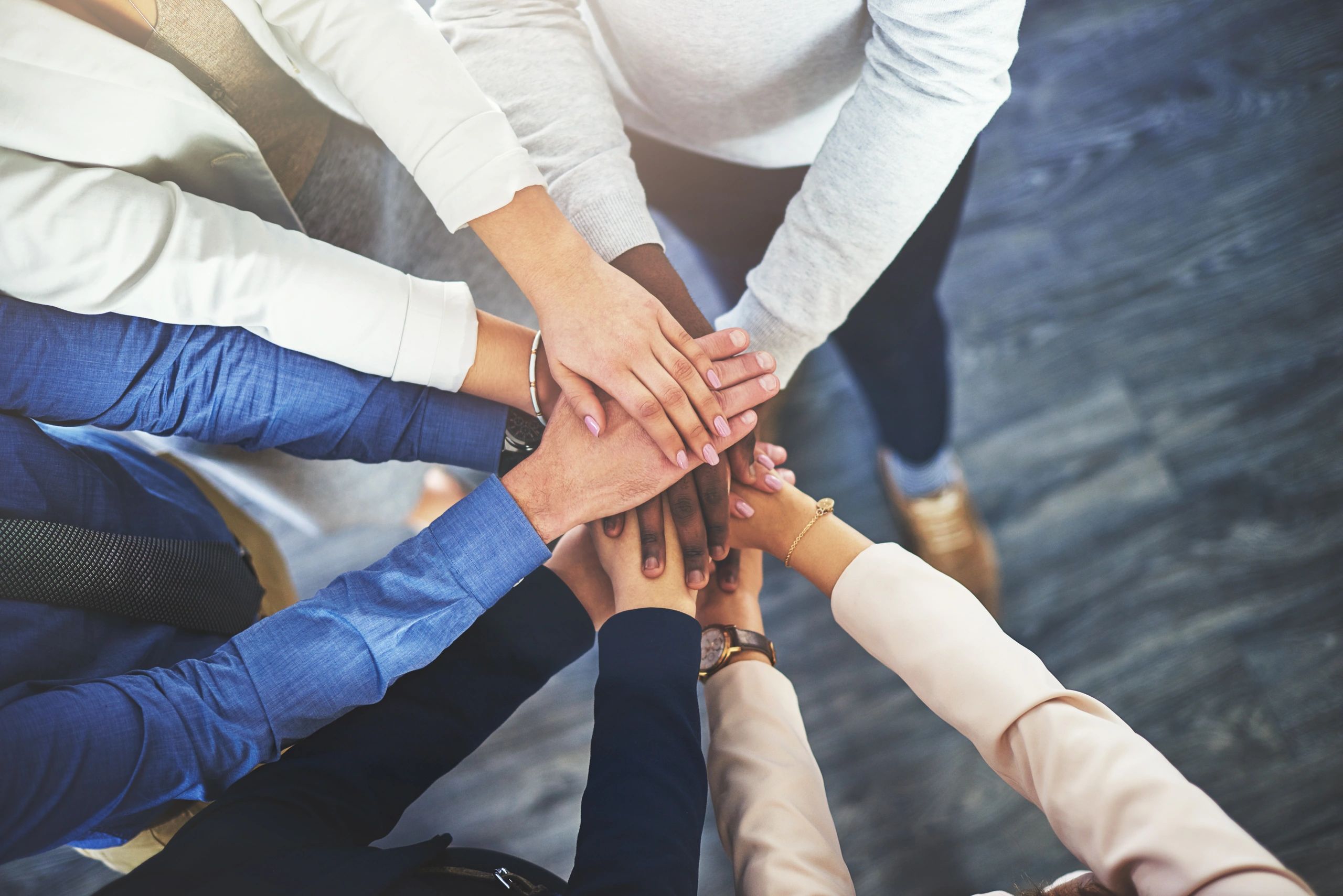 Diverse group stacking hands in teamwork gesture