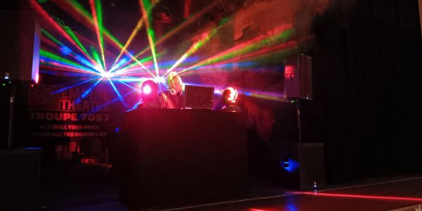 DJ performing with colorful laser lights in a dark venue.