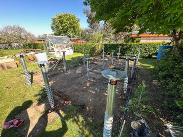 Metal foundation screws installed in a garden for a structure base.