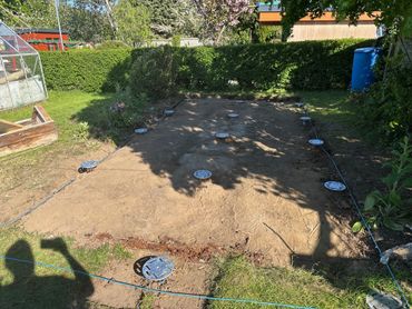 A cleared garden plot with irrigation system and surrounding greenery.