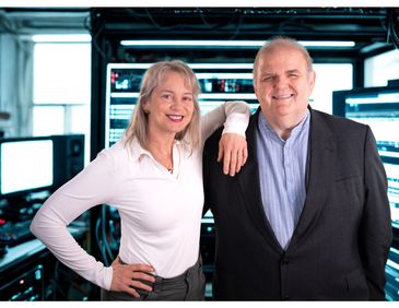 Two professionals smiling in a tech environment.