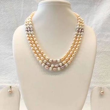 Elegant triple-strand pearl necklace with silver accents on a white display stand.