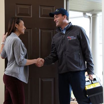 Man shaking hands with woman at her door.