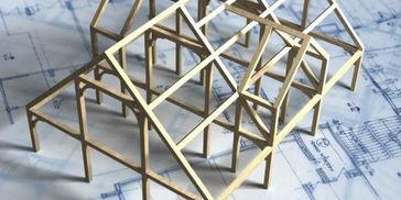 A wooden model framework of a house on architectural blueprints.