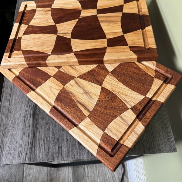 Two artistic wooden cutting boards with curved patterns.
