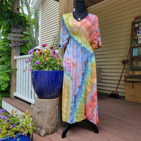 Colorful tie-dye dress displayed on a mannequin outside a porch with flowers.