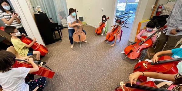 Woman teaching violin to a group of kids