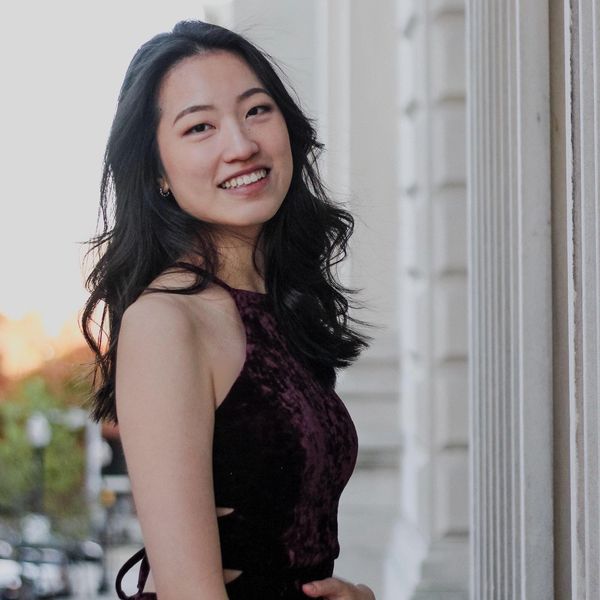 Anita Kuo dressed in purple, smiling, and posing for a photo