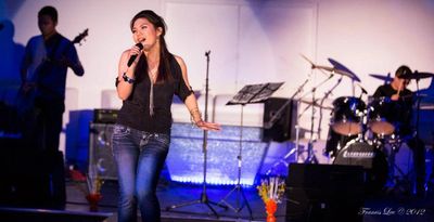 Female singer performing on stage with band.