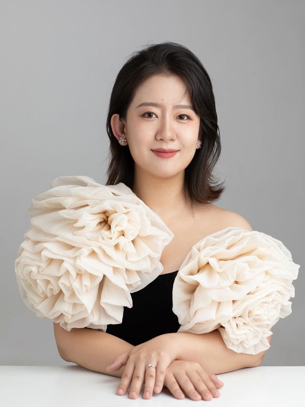 A smiling woman with open hair and a floral design dress