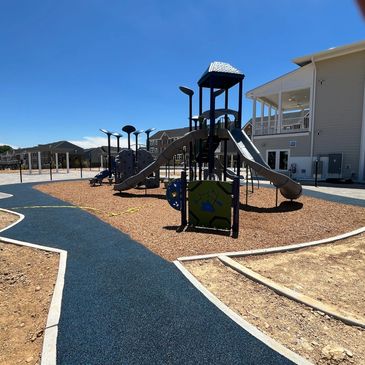 A modern playground with slides and climbing structures, featuring freshly installed mulch applied quickly using Gold Leaf Group's blower truck services.