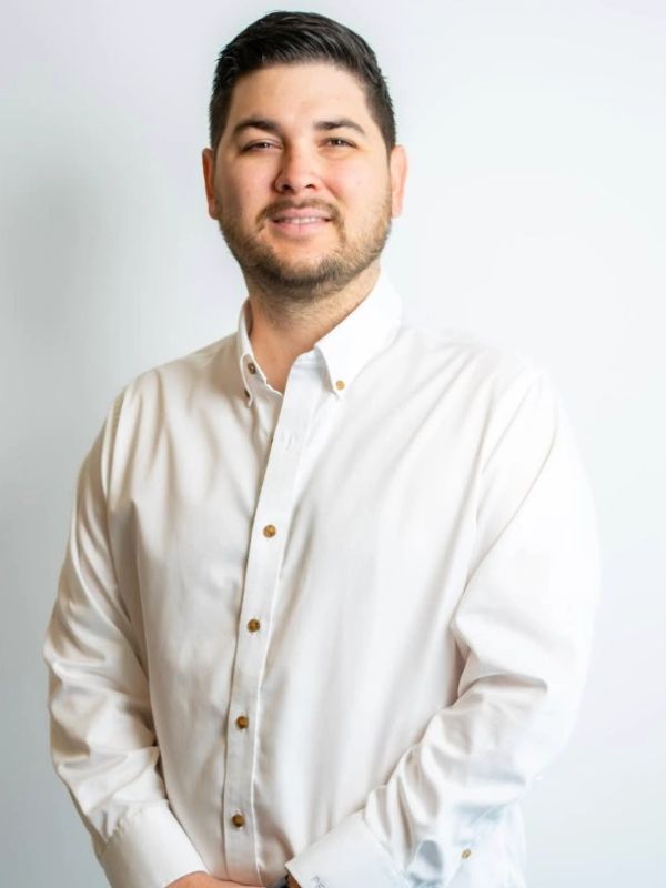 Man smiling, wearing a white button-up shirt.