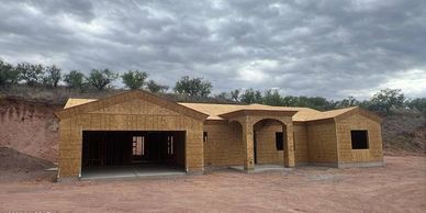House under construction with wood framing on a cloudy day.