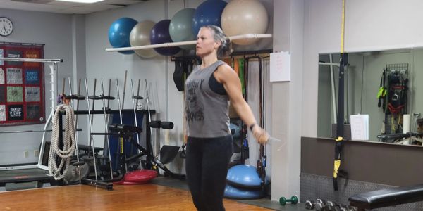 A woman skipping rope in a gym filled with fitness equipment.