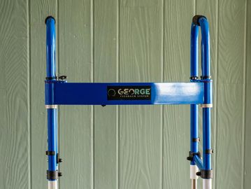 Blue walker frame against a green wooden wall.