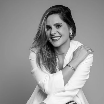 Black and white portrait of a smiling woman in a white blazer.