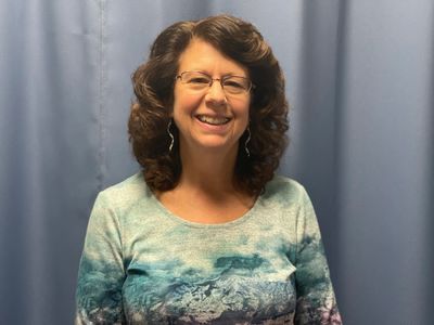 Woman standing in front of blue curtain in chiropractic office.