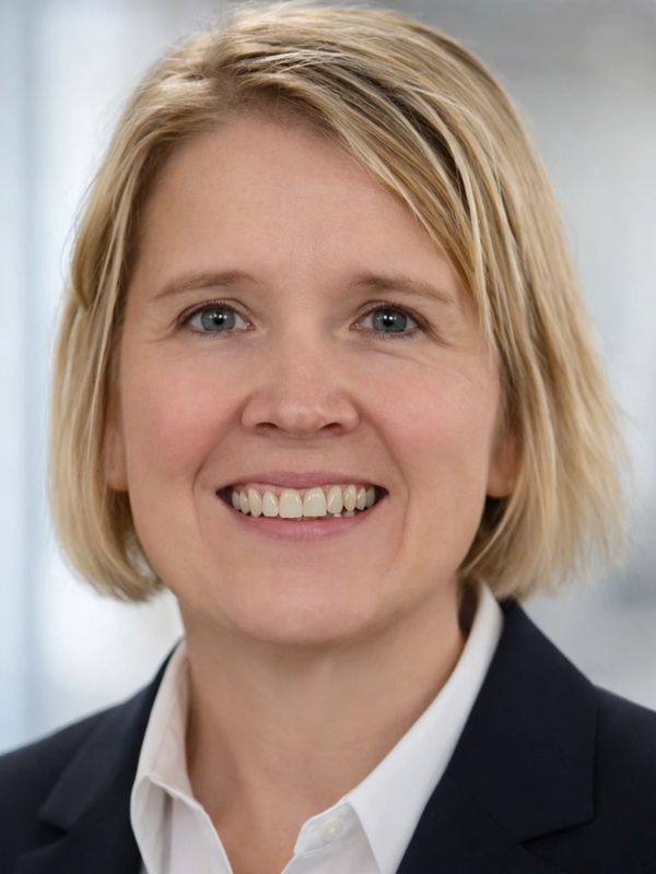 Smiling professional woman with short blonde hair in business attire.