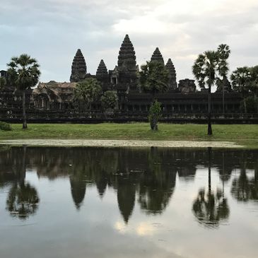 Angkor Wat temple reflected in a serene body of water at dusk.