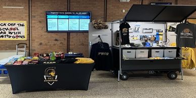 A promotional booth with snacks and merchandise against a brick wall.