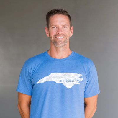 Man wearing a blue T-shirt with a 'Be Resilient' graphic of a state outline.