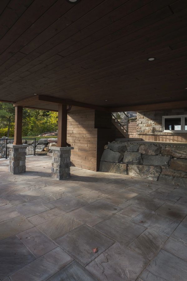 Covered patio with stone flooring and wooden ceiling.