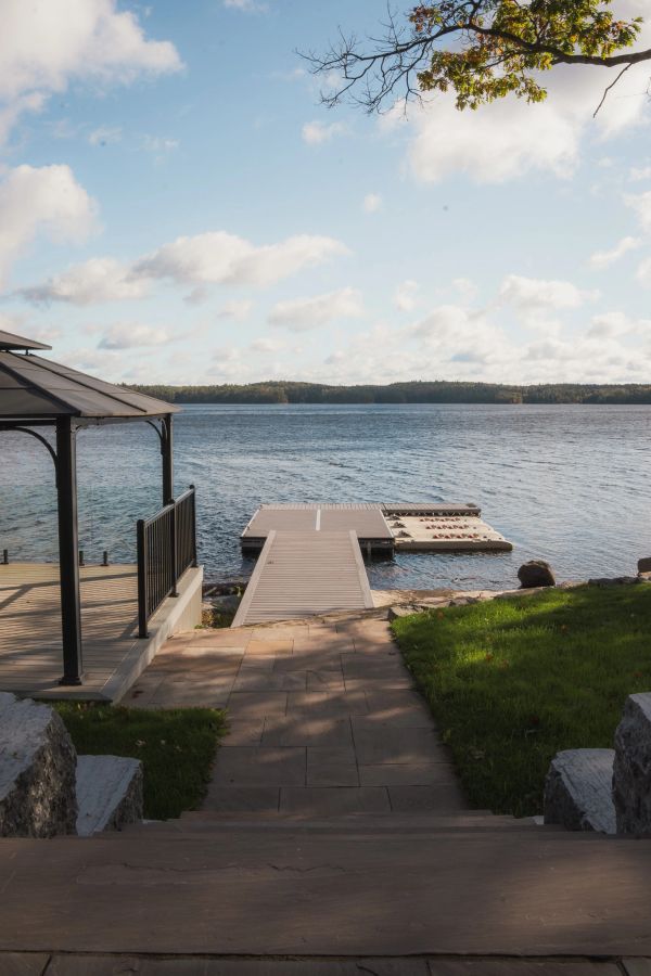 A wooden dock extending into a lake under a blue sky.