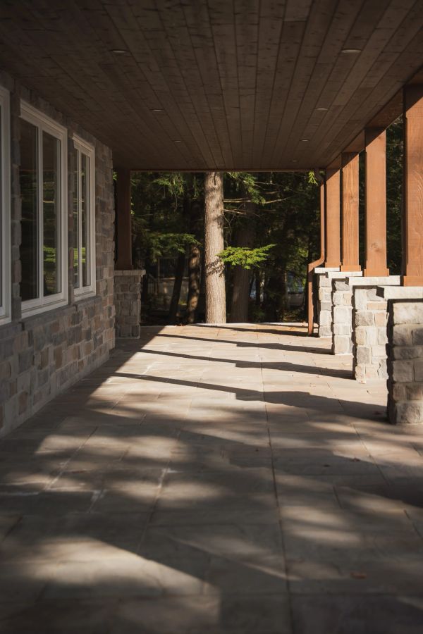 Covered stone patio with wooden ceiling and pillars.