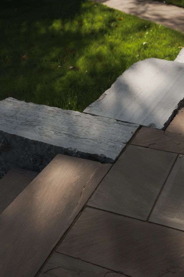 Stone steps and wall beside grass and sidewalk.