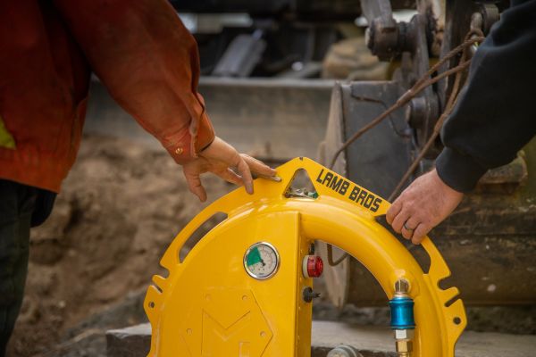 Two people handling a yellow Lamb Bros device.