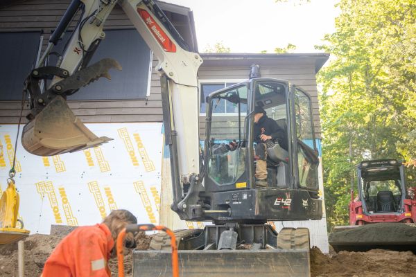 Construction workers operating excavator and tools.